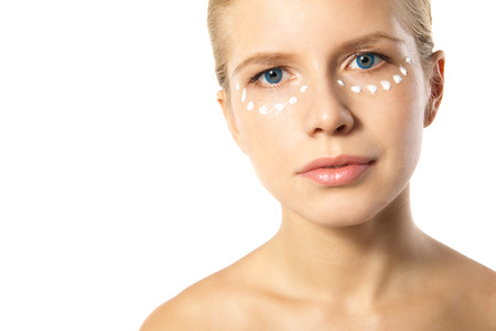 Portrait of young woman applying moisturizer cream on clean fresh face isolatedの写真素材