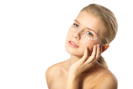 Portrait of young woman applying moisturizer cream on clean fresh face isolatedの写真素材