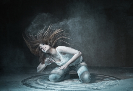 Emotional sexy Wild Woman with Flying hair and ashes in jeans over dark の写真素材