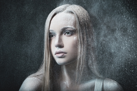Portrait of young, beautiful and emotional blonde woman over blowing wind and snowy blizzardの写真素材