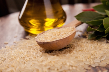 uncooked brown rice with spoon, olive oil and woody backgroundの写真素材