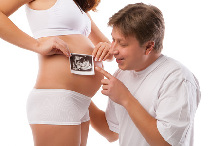Pregnant woman and her husband is holding her stomach and a photo of her Ultrasoundの写真素材