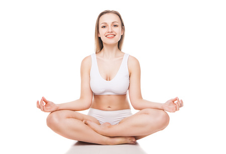 Young woman sitting in lotus position isolated over white backgroundの写真素材