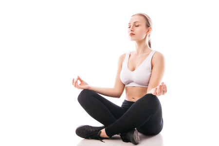 Young woman sitting in lotus position isolated over white backgroundの写真素材