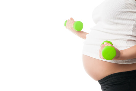 Sportive pregnant girl lifting dumbbells isolated on white background, workout indoors, sport for expectant female, healthy pregnancy conceptの写真素材
