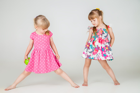 Two Little fashion girls in beautiful dress posing over white backgroundの写真素材
