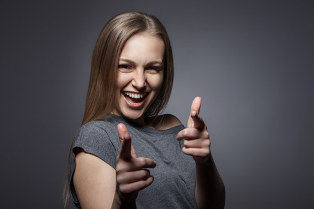 Portrait of happy smiling woman with okay gesture on dark grey backgroundの写真素材