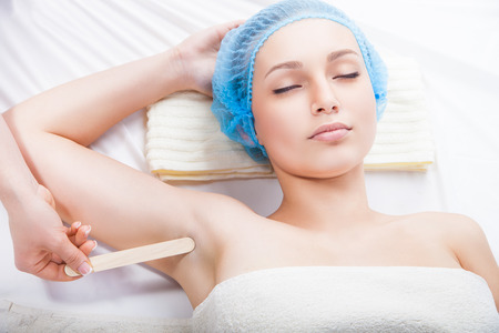 Close up of woman getting waxing armpit by beautician in a beauty salonの写真素材