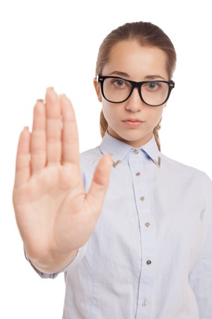 Serious young woman showing stop gesture, isolated over white backgroundの写真素材