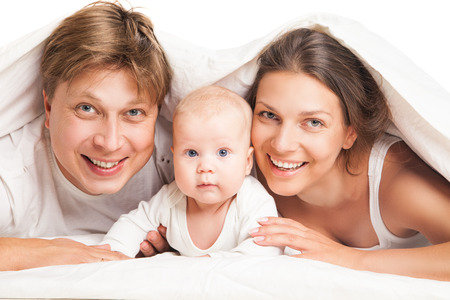 happy family, mother ,father and their baby under the blanket on the bed at homeの写真素材