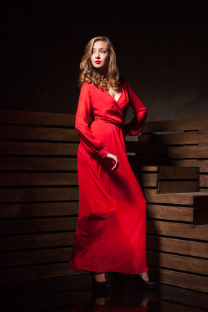 Portrait of Beautiful Sensual Woman in Long Fashion Red Dress over wooden backgroundの写真素材