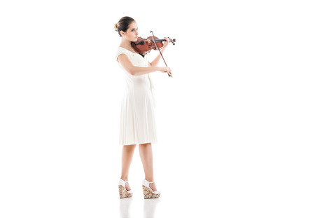 Beautiful young woman playing violin over white backgroundの写真素材