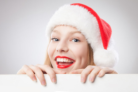 Beautiful christmas woman in santa hat holding empty board isolated on white backgroundの写真素材