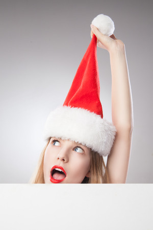 Beautiful christmas woman in santa hat holding empty board isolated on white backgroundの写真素材