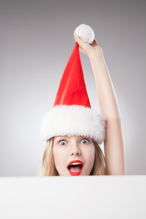 Beautiful christmas woman in santa hat holding empty board isolated on white backgroundの写真素材