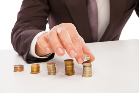 Business man calculating profit - closeup shot of hands counting coins isolated over whiteの写真素材