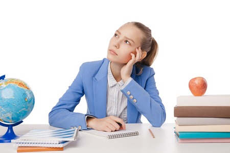 Thoughtful student sitting with many books, with her head in hand. Isolated over white background.の写真素材