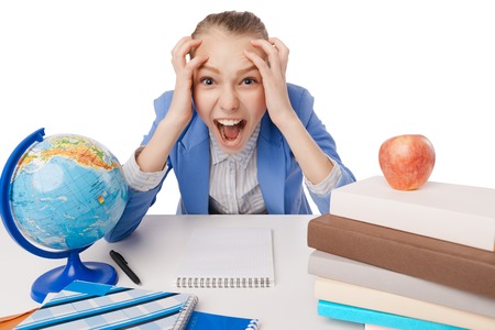 shouting and tired student girl with many book sitting at the table. Isolated over white background.の写真素材
