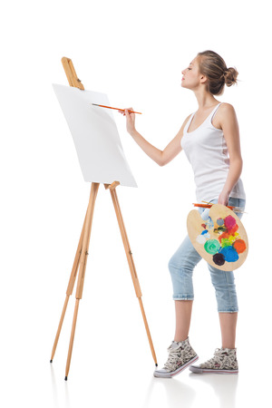 Girl paints on canvas with oil colors. Isolated.の写真素材