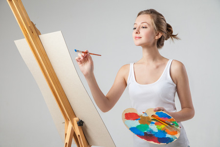 A close-up of smiling girl who  paints on canvas with oil colors. Isolated.の写真素材
