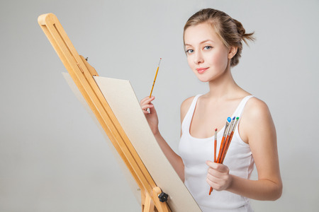 smiling girl with paintbrushes who is going to paint on canvas with oil colors. Isolated.の写真素材