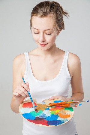 artist woman with paint palette who is mixing paints. Isolated.の写真素材