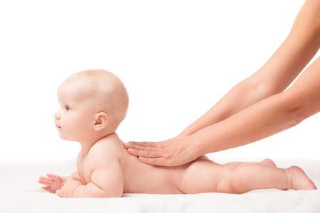 Cute baby lying on white blanket on stomach hands massaging his back. Isolated over white background.の写真素材