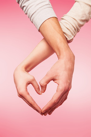 love and relationships concept -  closeup of woman and man hands showing heart shapeの写真素材
