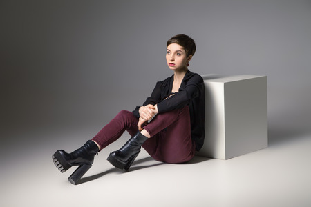 beautiful thin brunette woman  sitting on floor by cube her legs bentの写真素材