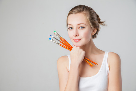 Close-up of smiling artist-girl with paintbrush. Isolated.の写真素材