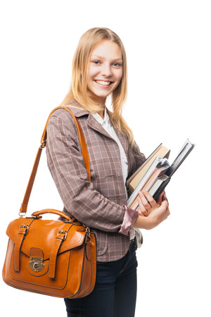 smiling young beautiful girl wearing jacket and jeans and standing sideways with brown bag and books   isolated on whiteの写真素材