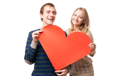 young smiling couple holding sign in form of red heart isolated on white backgroundの写真素材