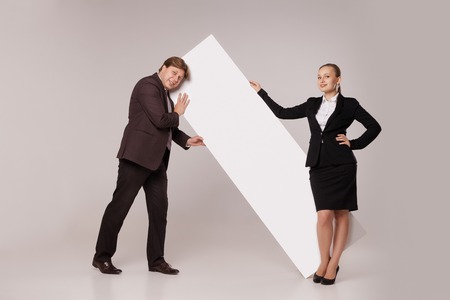 Business man and woman standing on both sides of blank banner, the man holding edge on the sholder.  isolated on grey background. Teamwork conceptの写真素材