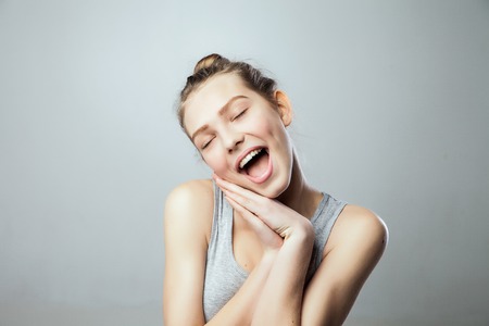 pretty young excited woman with her hands under chin, isolated against grey  backgroundの写真素材