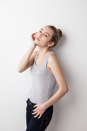 Closeup of woman standing against wall her hand touching face. Isolated over grey background.の写真素材