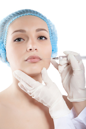 Beautiful woman gets an injection in her face close-up isolated on whiteの写真素材