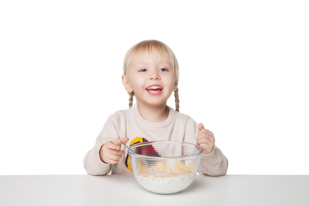 Smiling little girl eating breakfast. Isolated on white backgroundの写真素材