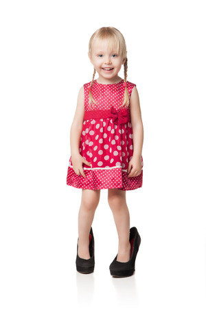 Smiling little girl wearing big shoes. Isolated on white backgroundの写真素材