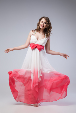 Elegant girl in fluttering dress posing at studioの写真素材