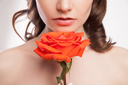 close-up portrait of beautiful brunette woman with red rose in her handの写真素材