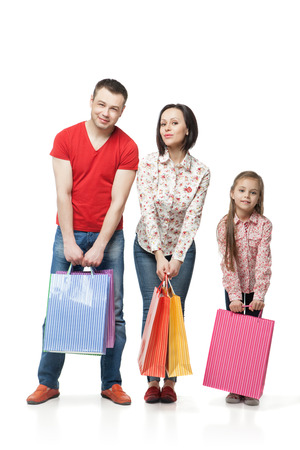Happy family with shopping bags standing at studio over white background.の写真素材