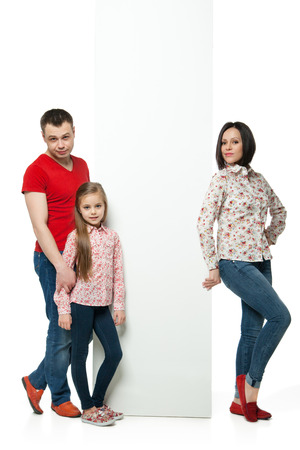Portrait of happy family standing behind billboard over white backgroundの写真素材