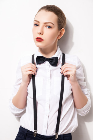 Elegant young woman holding her bow tie over white backgroudの写真素材