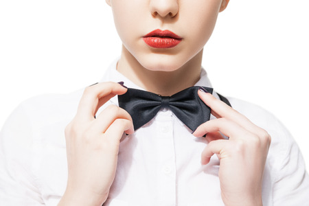 Close up portrait of a young woman in a white shirt and bow tie with red lipstick  on a white backgroundの写真素材