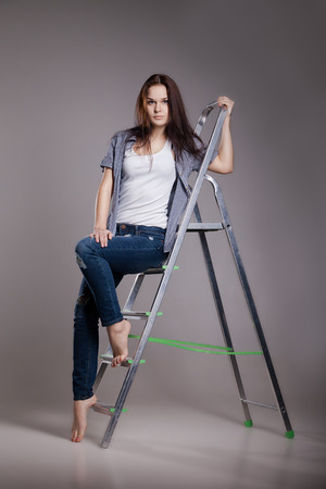 Young woman on step ladder. Isolated on white.の写真素材