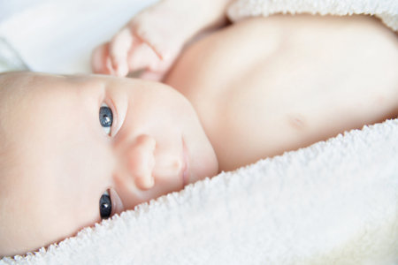 newborn tiny baby lying on the bed and looking aside. close-upの写真素材