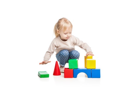 Baby girl building from toy blocks. Isolated on white backgroundの写真素材