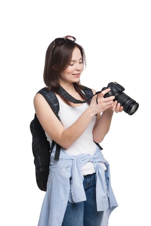 Young female tourist with backpack looking to her camera. Isolated on whiteの写真素材