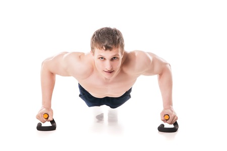 Muscular shirtless sportsman making push-ups in studio isolated on white backgroundの写真素材