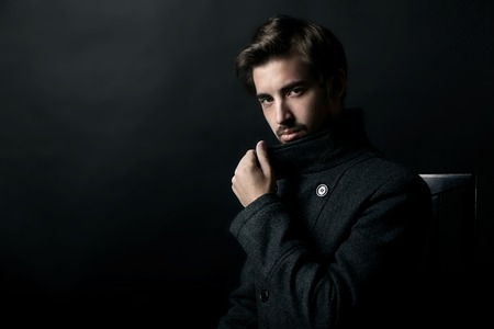 Fashion Shot of a young handsome man in coat on black backgroundの写真素材